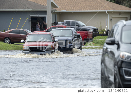 Flooded Florida road with evacuating cars and surrounded with water houses in suburban residential area. Consequences of hurricane natural disaster Flooded Florida road with evacuating cars and surrounded with water houses in suburban residential area. Consequences of hurricane natural disaster 124140831