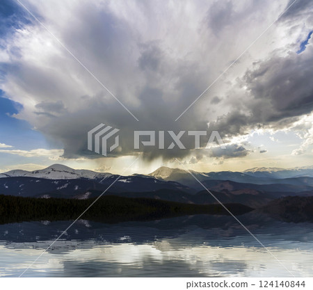 Fantastic view of huge white dark foreboding stormy cloud covering blue sky low over mountains Hoverla and Petros in Carpathian mountains range with bright snow on tops. Beauty and power of nature. 124140844