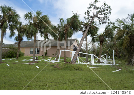Fallen down big tree caused damage of yard picket fence after hurricane in Florida. Consequences of natural disaster 124140848