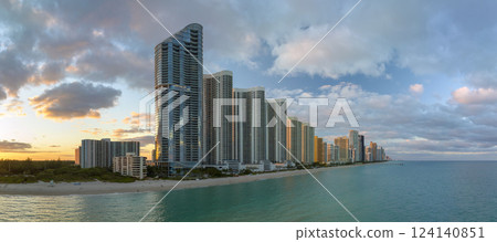 Expensive highrise hotels and condos over sandy beachfront on Atlantic ocean shore in Sunny Isles Beach city at sunset. American tourism infrastructure in southern Florida Expensive highrise hotels and condos over sandy beachfront on Atlantic ocean shore in Sunny Isles Beach city at sunset. American tourism infrastructure in southern Florida 124140851