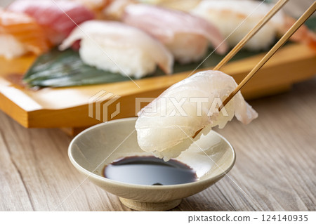 Pick up delicious looking sushi on a plate with chopsticks 124140935