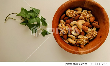 Nuts and green leaves on a wooden plate 124141286