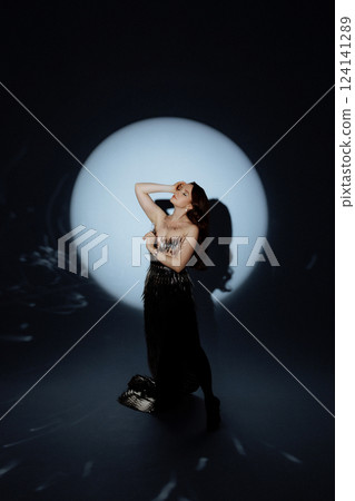 Glamorous Woman in a Metallic Dress Posing Under Dramatic Spotlight 124141289