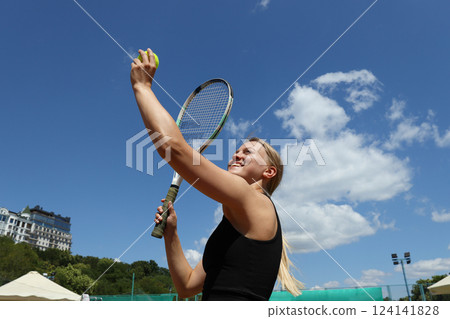 A blonde girl plays tennis on the sports court. 124141828