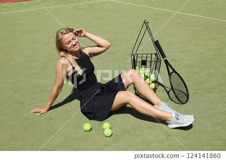 A blonde girl plays tennis on the sports court. 124141860