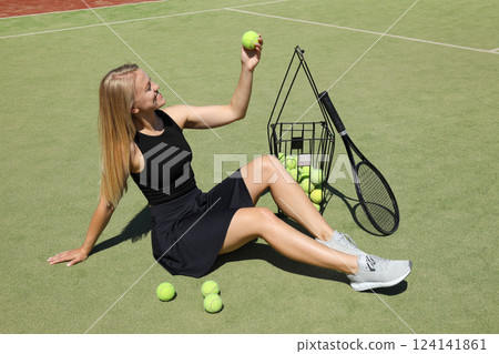 A blonde girl plays tennis on the sports court. 124141861