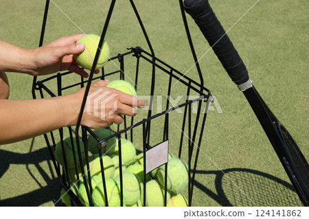 The girl is holding a racket and balls for big tennis. 124141862