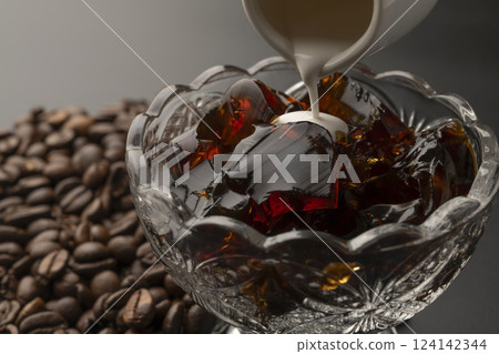 Cold coffee jelly served in a glass bowl with milk poured over it Coffee beans Cold coffee jelly served in a glass bowl with milk poured over it Coffee beans 124142344