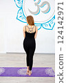 Woman in black sportswear standing on a yoga mat 124142971