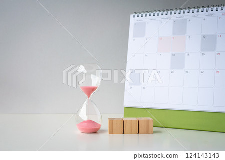 Sand timer with three blank wooden toy blocks next to a calendar. 124143143