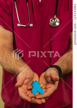 Healthcare worker presents a blue awareness ribbon in a clinic setting Healthcare worker presents a blue awareness ribbon in a clinic setting 124143861