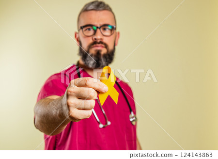 Cardiologist holding a yellow awareness ribbon in a clinic setting 124143863