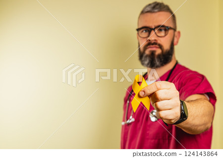 Healthcare professional showing support with yellow ribbon indoors 124143864