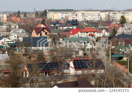 A rooftop solar panel installation on a house in Ukraine, capturing the sun rays to generate clean energy. The panels are arranged on the roof, with a view of the home in the background 124145373