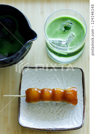 Glass of fresh matcha tea, green tea with coconut water and Mitarashi dango, traditional Japanese confectionery on wooden table. 124146148