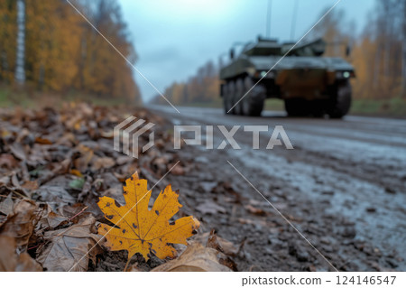 military equipment on a dirt road behind autumn foliage in the foreground 124146547