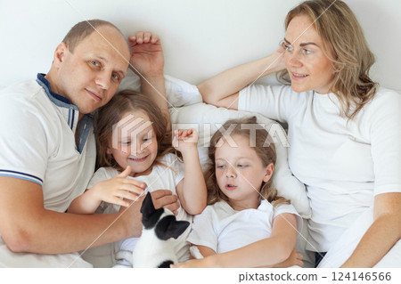 Positive parents and their daughter having fun on a bed indoors 124146566