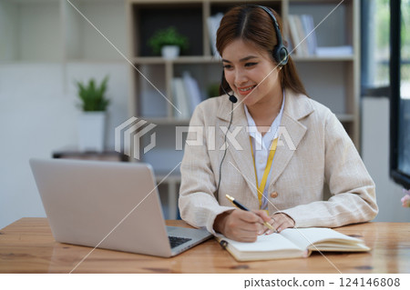 Asian businesswoman wears a headset while participation in an online video conference discussing marketing and finance strategies effectively Asian businesswoman wears a headset while participation in an online video conference discussing marketing and finance strategies effectively 124146808