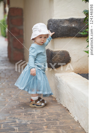 Pretty little baby girl toddler in blue dress, outdoor portrait 124146898
