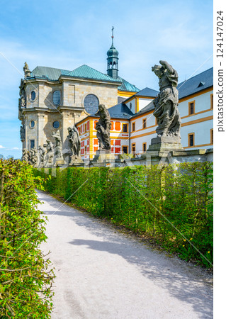 Tall Baroque statues stand along a walkway at the Kuks hospital complex in Czechia, showcasing intricate designs near the historical architecture of the site. 124147024