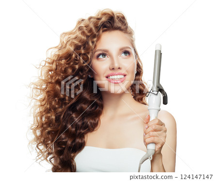 Joyful brown haired woman with shiny long curly hairstyle showing curling iron. 124147147