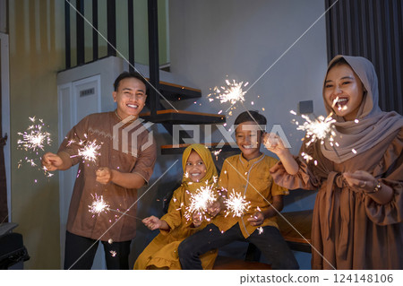 An Indonesian Muslim family playing fireworks in their hometown. Concept of Happy Lebaran, Eid Al Fitr, Idul Fitri, and Ramadan Mubarak celebration 124148106