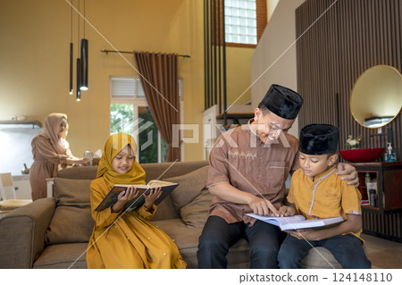 Portrait of an Indonesian Muslim father teaching his child to read the quran. Waiting for time to iftar. Concept of Happy Lebaran, Eid Al Fitr, Idul Fitri, and Ramadan Mubarak celebration Portrait of an Indonesian Muslim father teaching his child to read the quran. Waiting for time to iftar. Concept of Happy Lebaran, Eid Al Fitr, Idul Fitri, and Ramadan Mubarak celebration 124148110