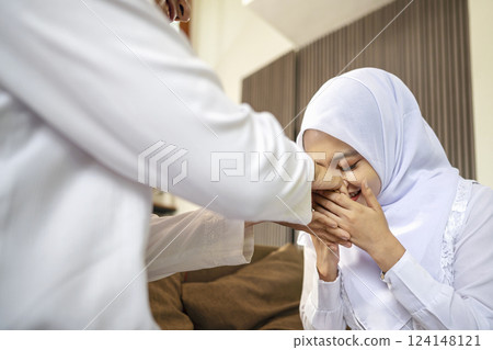 Portrait of the Indonesian Muslim wife asking forgiveness to her husband while celebrating Eid Mubarak. Concept of Happy Lebaran, Eid Al Fitr, Idul Fitri, and Ramadan Mubarak celebration 124148121