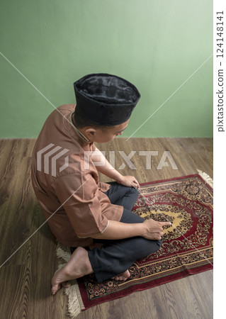 Portrait of an Indonesian muslim man praying (salat) at home. Concept of Islamic praying or Ramadan Kareem Portrait of an Indonesian muslim man praying (salat) at home. Concept of Islamic praying or Ramadan Kareem 124148141