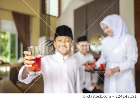 Portrait of the Indonesian Muslim boy holding a drink while celebrating Eid Mubarak. Concept of Happy Lebaran, Eid Al Fitr, Idul Fitri, and Ramadan Mubarak celebration 124148151