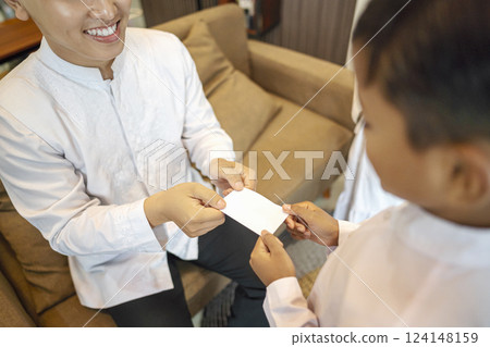 Portrait of the Indonesian Muslim father giving his son an envelope of money (Thr) while celebrating Eid Mubarak. Concept of Happy Lebaran, Eid Al Fitr, Idul Fitri, and Ramadan Mubarak celebration Portrait of the Indonesian Muslim father giving his son an envelope of money (Thr) while celebrating Eid Mubarak. Concept of Happy Lebaran, Eid Al Fitr, Idul Fitri, and Ramadan Mubarak celebration 124148159