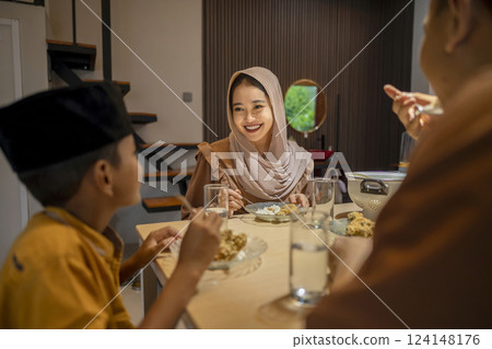 Portrait of Indonesian Muslim family breaking their fasting together at home. Concept of Happy Lebaran, Eid Al Fitr, Idul Fitri, and Ramadan Mubarak celebration 124148176