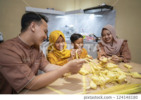 Indonesian Muslim family weaving ketupat rice dumpling from young coconut leaves. Traditional Muslim food during celebration of Happy Lebaran, Eid Al Fitr, Idul Fitri, and Ramadan Mubarak celebration Indonesian Muslim family weaving ketupat rice dumpling from young coconut leaves. Traditional Muslim food during celebration of Happy Lebaran, Eid Al Fitr, Idul Fitri, and Ramadan Mubarak celebration 124148180