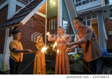 Asian Muslim family playing fireworks at hometown. Concept of Eid Al Fitr, Idul Fitri, and Ramadan Mubarak celebration 124148613