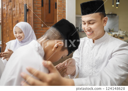Portrait of the Indonesian Muslim boy asking forgiveness to his father while celebrating Eid Mubarak. Concept of Happy Lebaran, Eid Al Fitr, Idul Fitri, and Ramadan Mubarak celebration 124148628