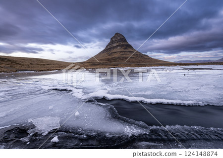 Flowing water from Kirkjufellsfoss waterfall with a view of Kirkjufell mountain on peninsula, Iceland Flowing water from Kirkjufellsfoss waterfall with a view of Kirkjufell mountain on peninsula, Iceland 124148874