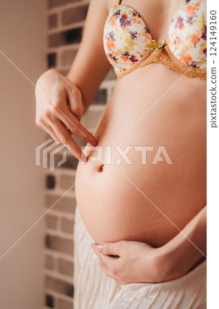 Young pregnant woman gently touching her belly in a cozy indoor setting 124149160