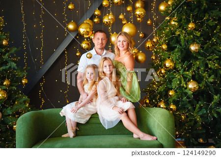 A happy family in elegant clothes on a green sofa at the Christmas tree. A happy family in elegant clothes on a green sofa at the Christmas tree. 124149290