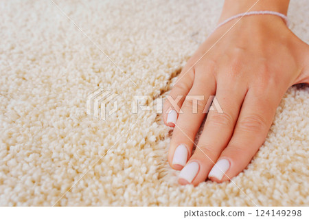a woman's hand touching the beige Interior pile carpet made of polypropylene.  124149298