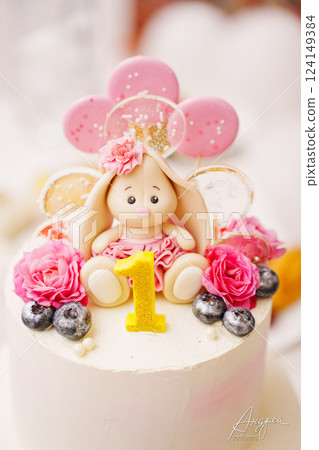 Children's festive two-tiered cake decorated with flowers and a bunny for a girl Children's festive two-tiered cake decorated with flowers and a bunny for a girl 124149384