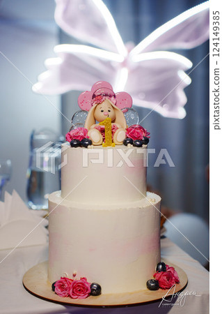 Children's festive two-tiered cake decorated with flowers and a bunny for a girl Children's festive two-tiered cake decorated with flowers and a bunny for a girl 124149385