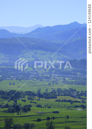 Breathtaking green valley surrounded by misty blue mountains in rural landscape 124149688