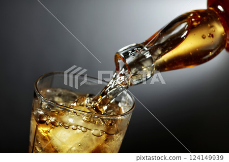 Whiskey being poured into glass with ice. 124149939