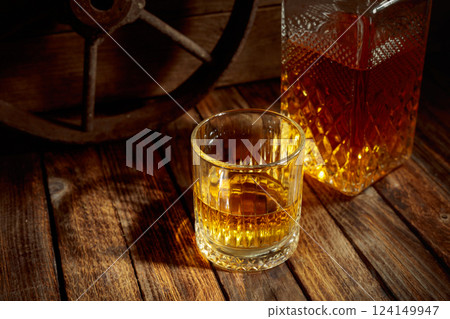 Elegant whiskey glass and decanter on a old wooden table. Elegant whiskey glass and decanter on a old wooden table. 124149947