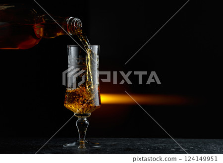 Hard liquor being poured into a glass. Hard liquor being poured into a glass. 124149951