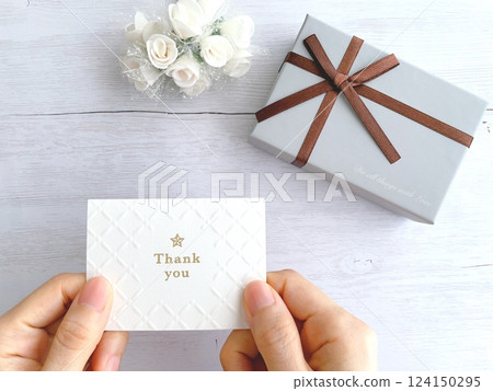 Hands holding a thank you message card and a gift Hands holding a thank you message card and a gift 124150295