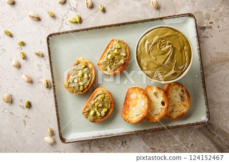 Vegetarian Pistachio cream, toasted bread and raw nuts close-up on table. Horizontal top view Vegetarian Pistachio cream, toasted bread and raw nuts close-up on table. Horizontal top view 124152467