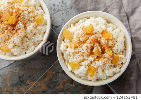 Sweet rice pudding with cinnamon and raisins on top close-up in a ramekin. Horizontal top view Sweet rice pudding with cinnamon and raisins on top close-up in a ramekin. Horizontal top view 124152481