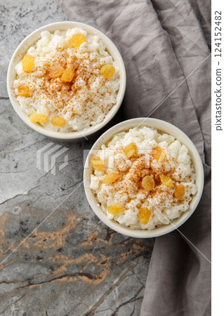 Delicious rice pudding with cinnamon, vanilla and raisins closeup on the bowl. Vertical top view Delicious rice pudding with cinnamon, vanilla and raisins closeup on the bowl. Vertical top view 124152482