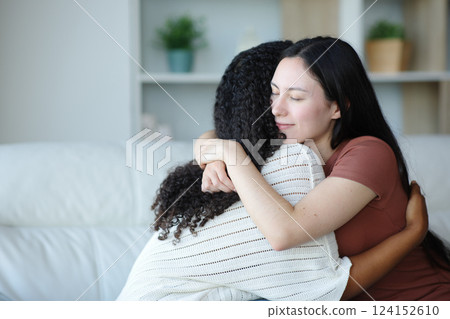 Satisfied asian woman hugging a black friend Satisfied asian woman hugging a black friend 124152610